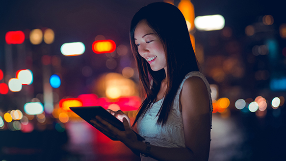 Woman holding tablet at night smiling