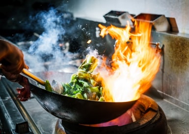 Tossing vegetables in a wok with flames